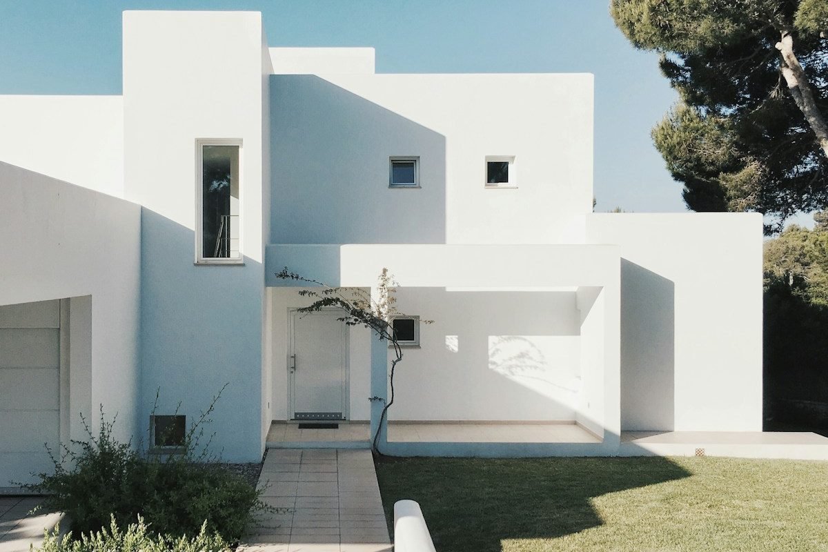 maison en béton blanc près d'un arbre vert pendant la journée