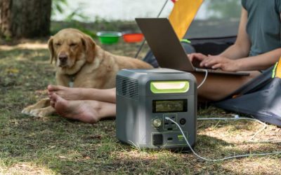 Station d'énergie portable de la série VOLIX utilisée pour charger un ordinateur portable lors d'un camping avec un chien