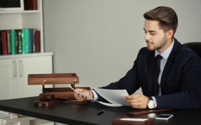 Un professionnel en costume assis à son bureau examine des documents juridiques pour un projet de création entreprise